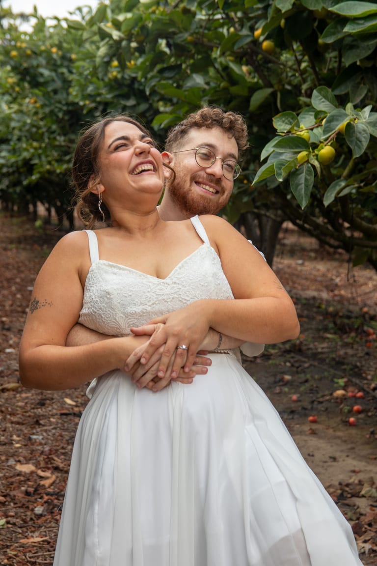 הכלה והחתן צוחקים ומתחבקים בין העצים