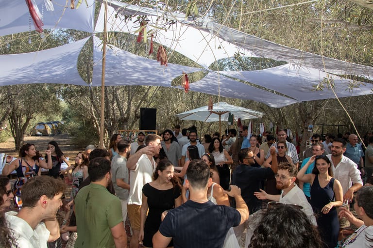 אורחים רוקדים מתחת לסוכך ולשמשיות