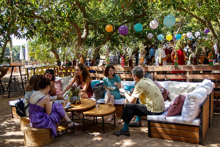 אורחים יושבים בפינת ישיבה מתחת לפנסי נייר