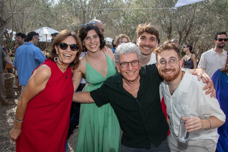 ארבעה אורחים מצטופפים בחיבוק וצוחקים למצלמה