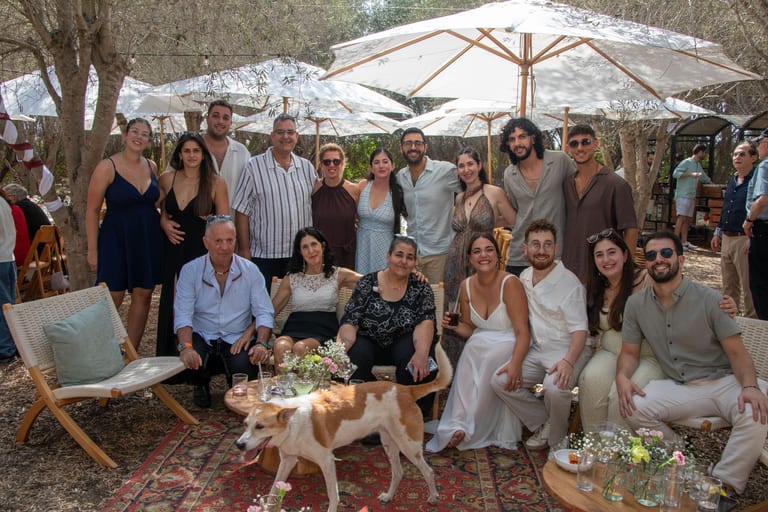 קבוצת אורחים מצטלמת על שטיח עם כלב